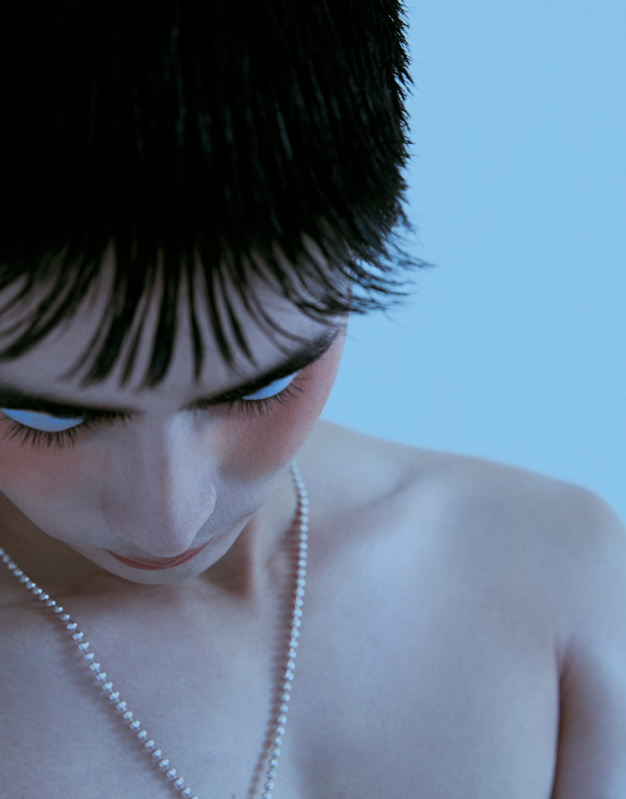 Man with blue eyeshadow and pearl necklace
