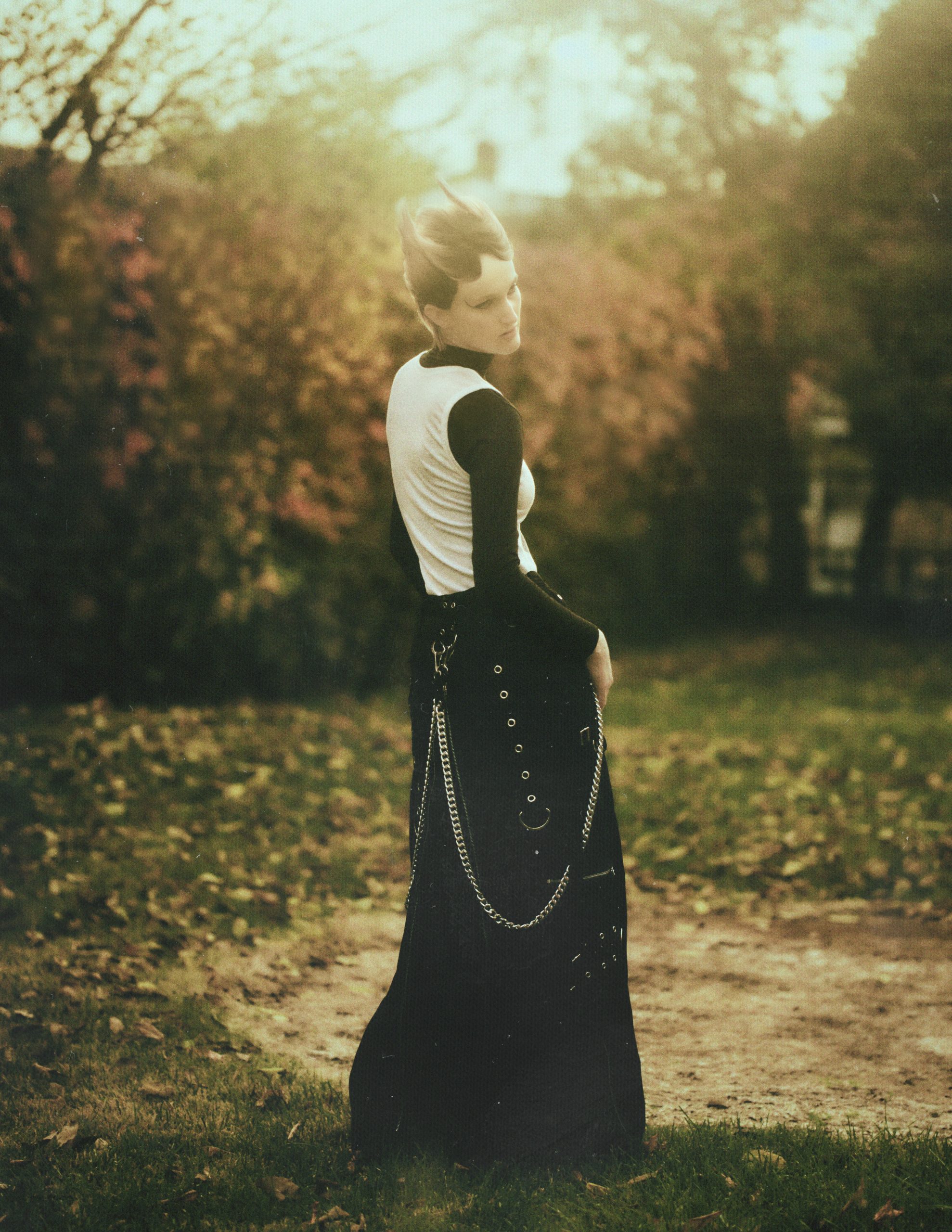 woman wearing a long black skirt with chains standing on grass