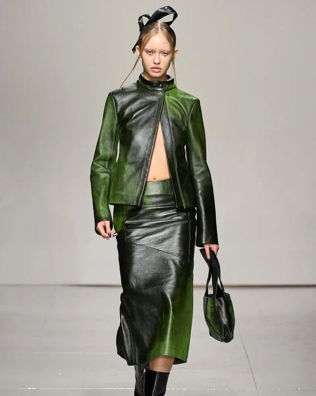Model walking down the runway in green leather