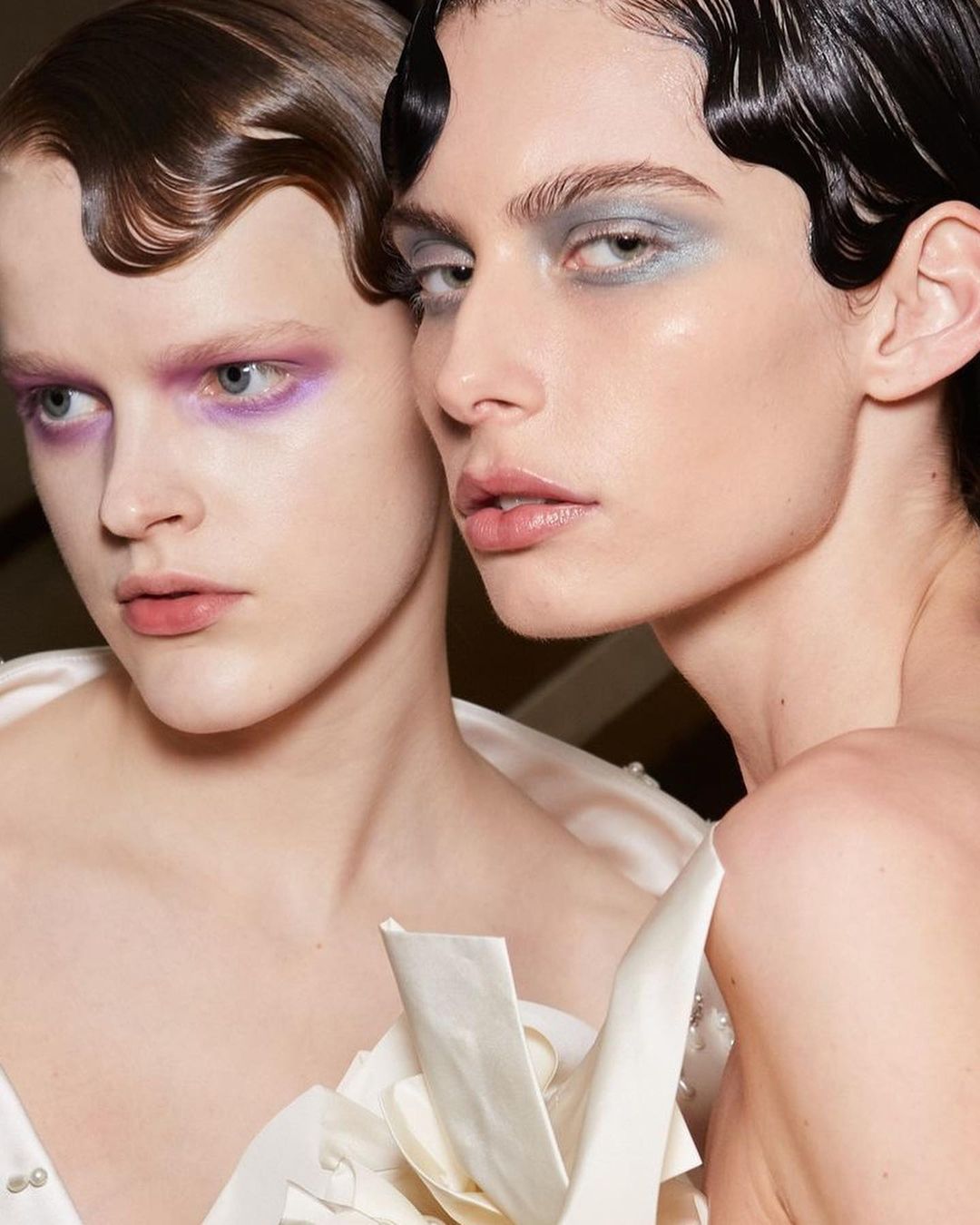 Two models with wavy hair and colorful eyeshadow
