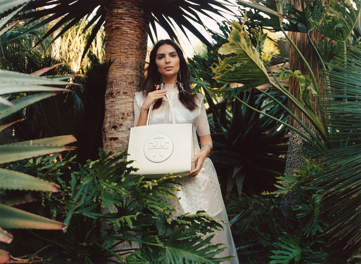 Frau hält weiße Tasche vor Palmen