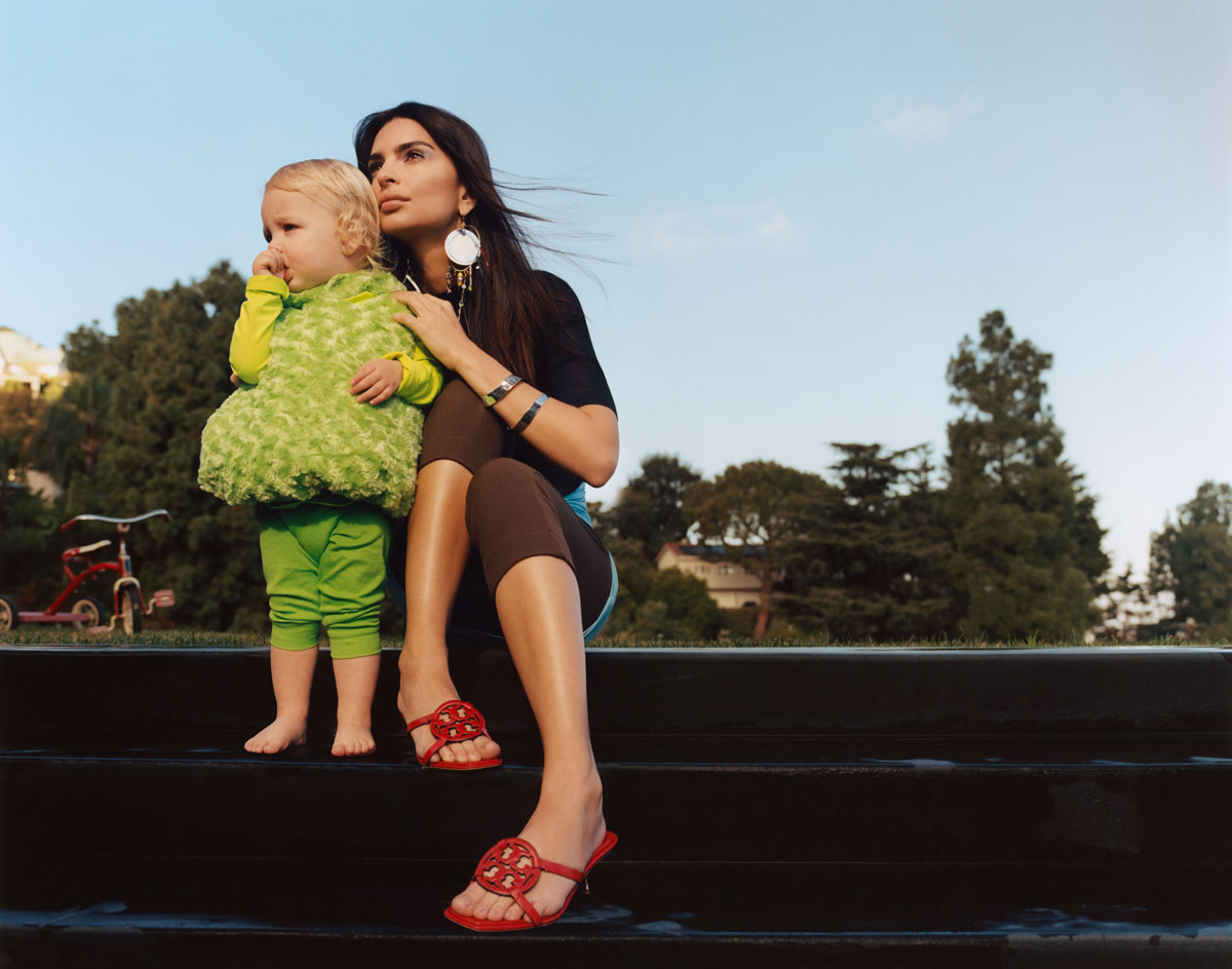 Woman holding a kid in green clothes in her arms